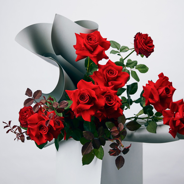 Букет красных роз в простой стеклянной вазе, украшенной бантом, смотрится одновременно скромно и по-королевски