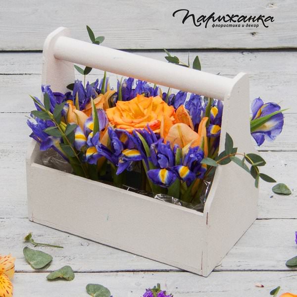 Композиция с оранжевыми розами и синими ирисами в деревянном ящике